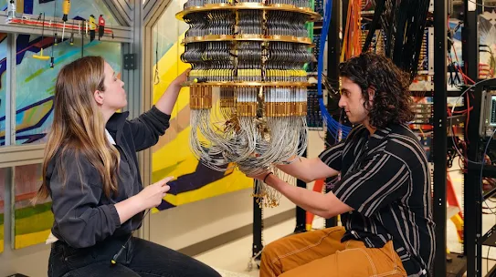 Two people work on installing a quantum processor into a dilution refrigerator.