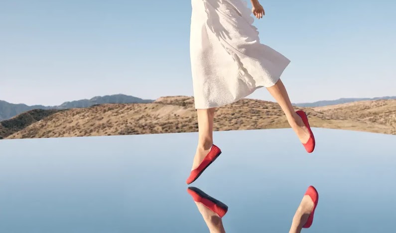 A model wearing Rothy's shoes over a mirror in the desert.